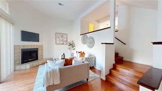 living room with light hardwood / wood-style floors and a tiled fireplace