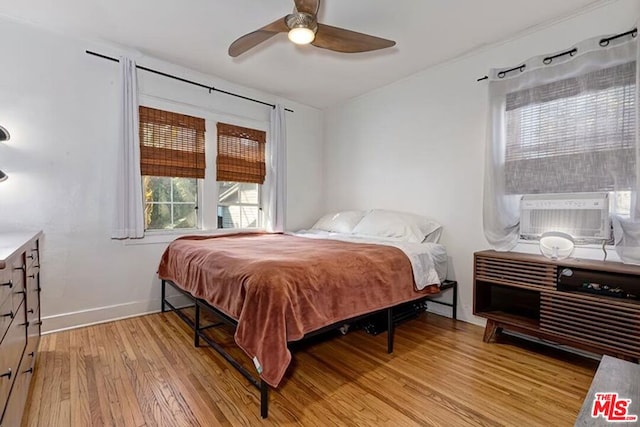 bedroom with cooling unit, ceiling fan, and light hardwood / wood-style floors