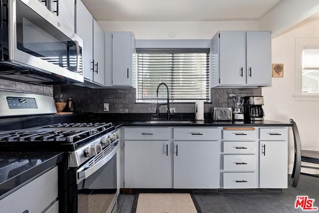 kitchen featuring sink, decorative backsplash, stainless steel appliances, and dark tile patterned floors