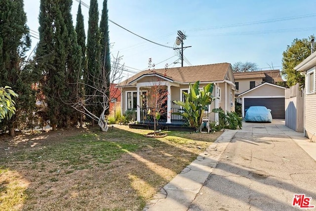 view of front of house with an outbuilding, a porch, a garage, and a front lawn