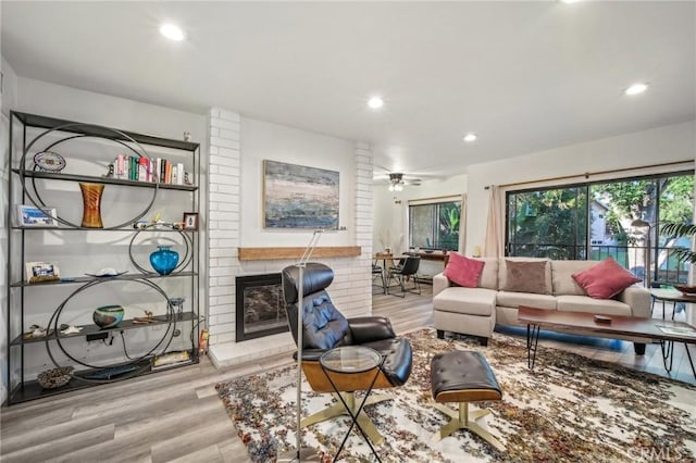 living room with ceiling fan, a fireplace, and light hardwood / wood-style flooring