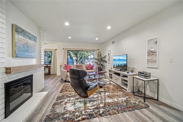 living room featuring light wood-type flooring and a brick fireplace