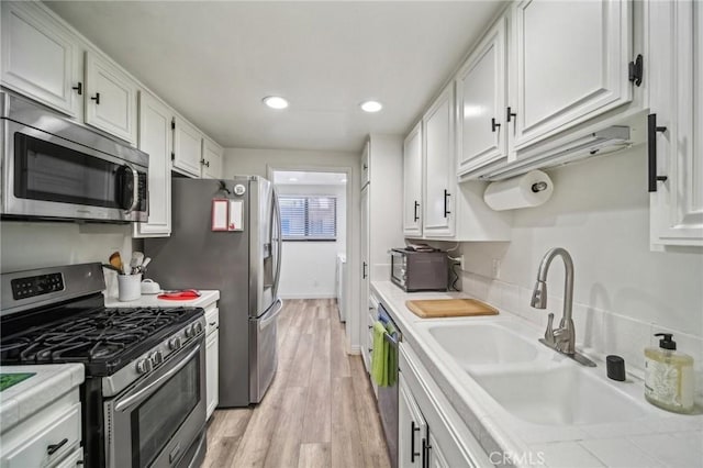 kitchen featuring stainless steel appliances, light hardwood / wood-style floors, white cabinetry, and sink