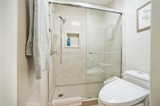 bathroom featuring toilet and a shower with door