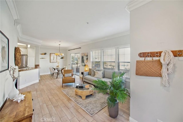 living room with sink, light wood-type flooring, a notable chandelier, and ornamental molding