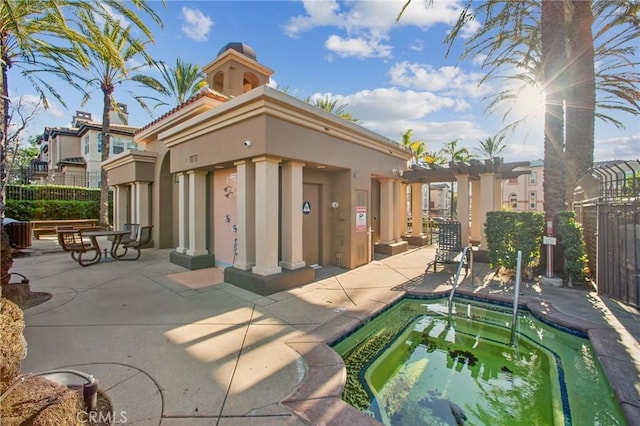 rear view of property with an in ground hot tub and a patio area