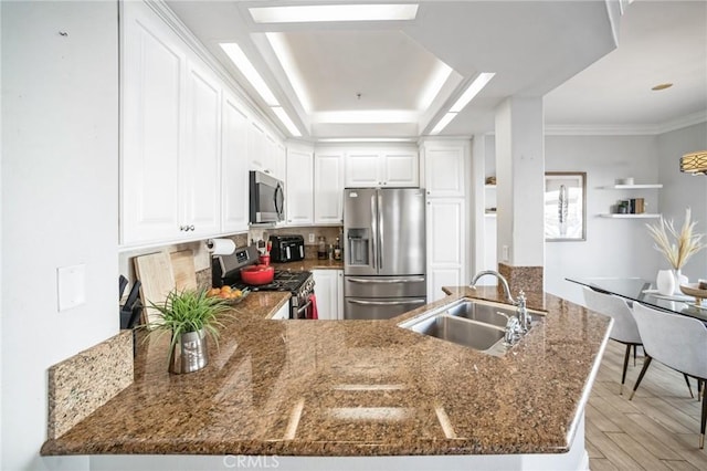 kitchen featuring white cabinetry, sink, light hardwood / wood-style flooring, kitchen peninsula, and appliances with stainless steel finishes