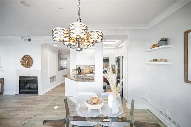 dining room with a notable chandelier, sink, and crown molding