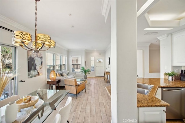 living room featuring crown molding, plenty of natural light, sink, and an inviting chandelier