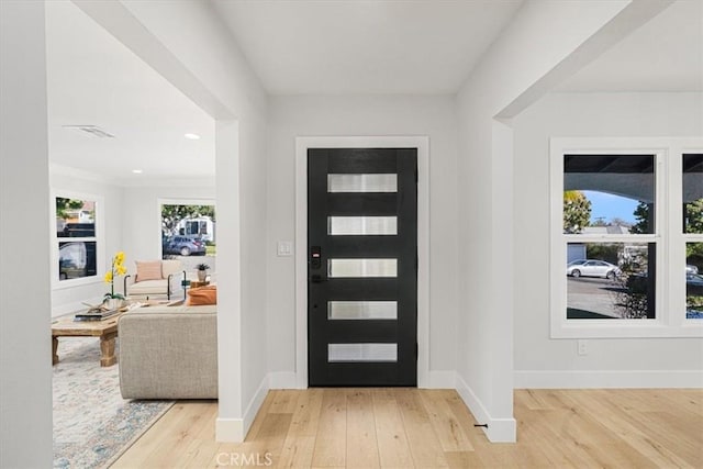 foyer entrance featuring light hardwood / wood-style flooring and ornamental molding