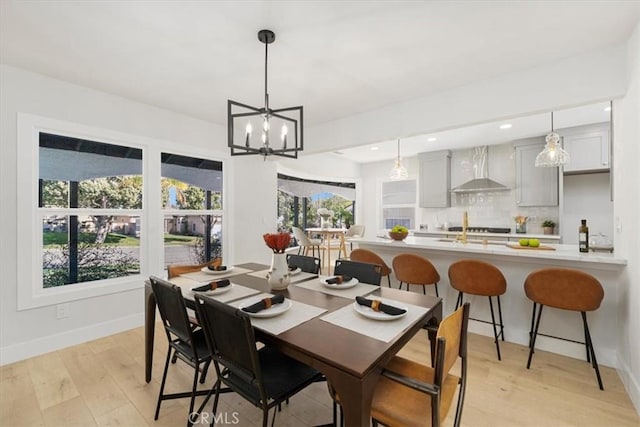 dining area with light hardwood / wood-style flooring and a notable chandelier