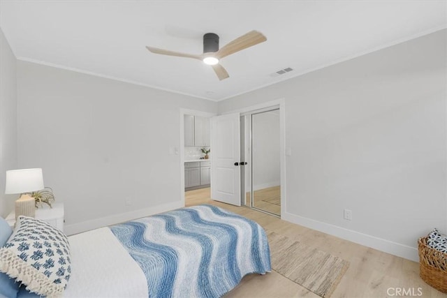 bedroom with crown molding, ceiling fan, a closet, and light hardwood / wood-style floors