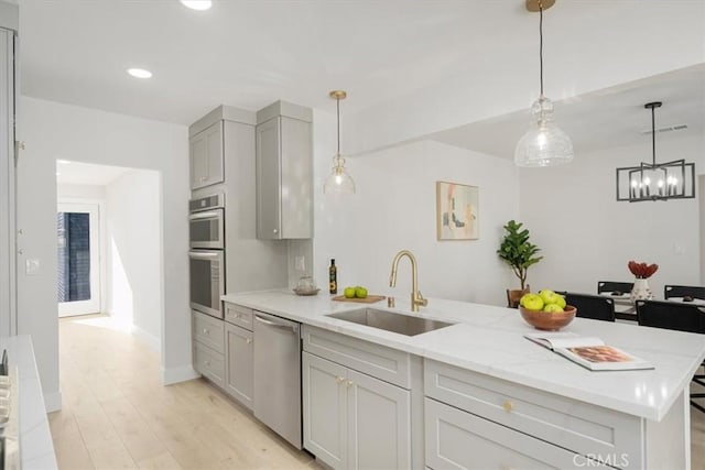 kitchen featuring light stone countertops, sink, light hardwood / wood-style floors, gray cabinets, and appliances with stainless steel finishes