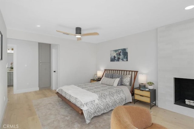 bedroom with ceiling fan, ensuite bathroom, and light hardwood / wood-style floors