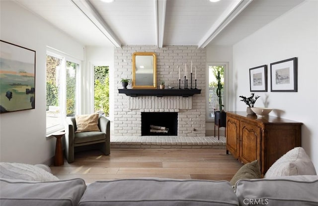 living room with light wood-type flooring, beamed ceiling, and a fireplace