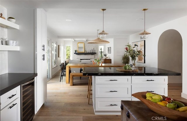 kitchen with decorative light fixtures, hardwood / wood-style floors, white cabinets, and wine cooler