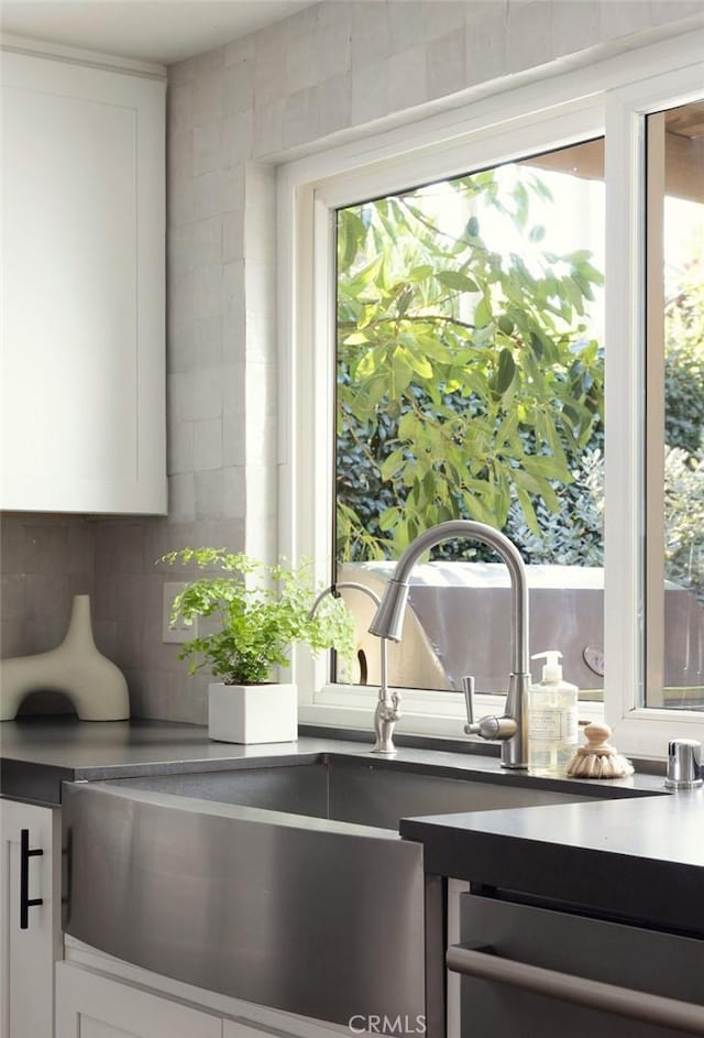 room details featuring white cabinetry, dishwasher, and tasteful backsplash