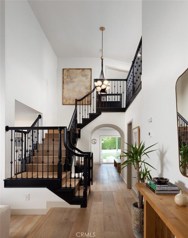 stairs with hardwood / wood-style flooring, a towering ceiling, and an inviting chandelier