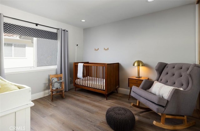 bedroom with light hardwood / wood-style flooring and a crib