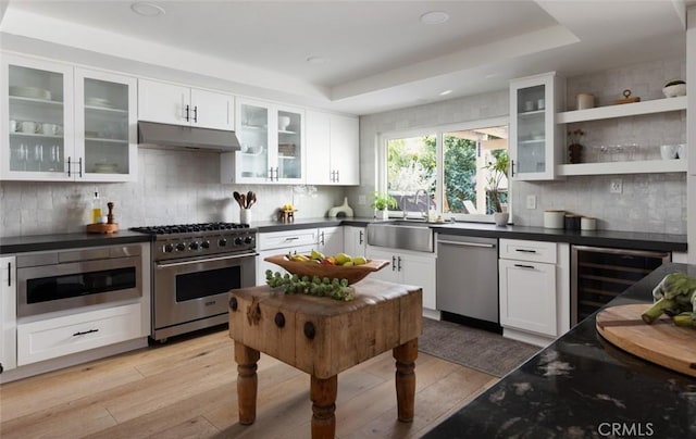 kitchen featuring white cabinets, appliances with stainless steel finishes, sink, a raised ceiling, and light wood-type flooring