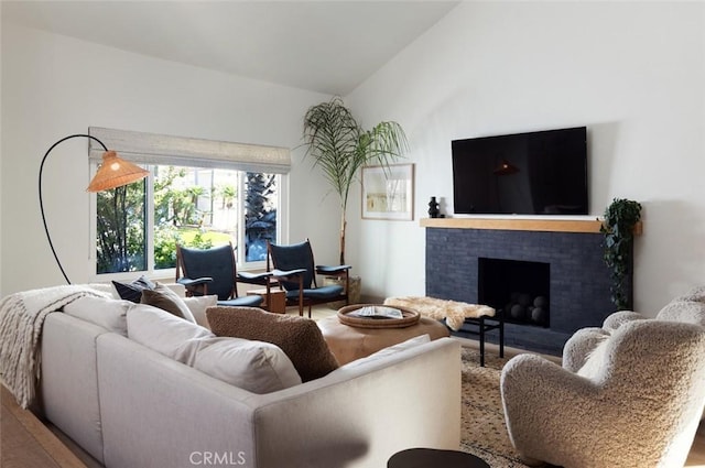 living room featuring a brick fireplace, hardwood / wood-style flooring, and vaulted ceiling