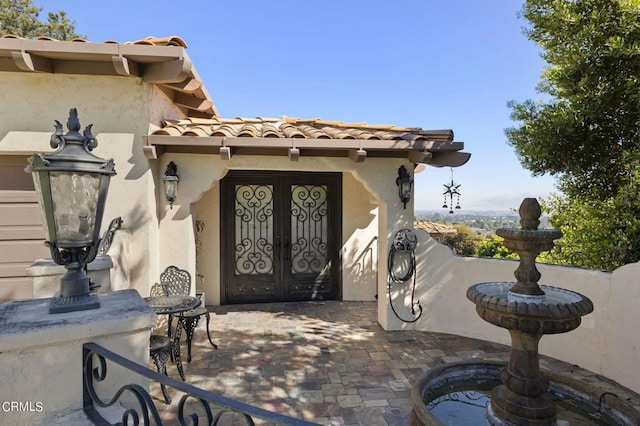 view of exterior entry with french doors and a patio area