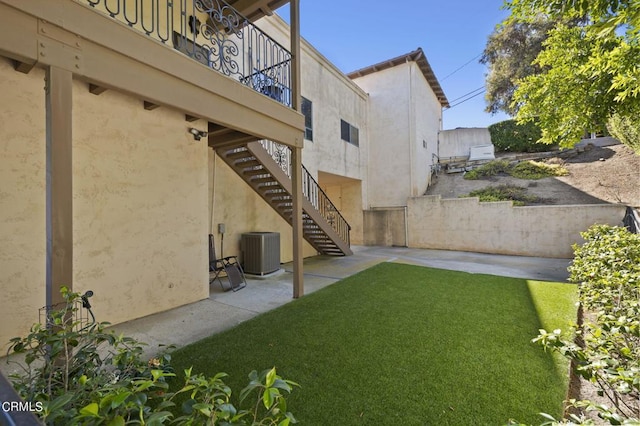 view of yard featuring a patio, a balcony, and central AC