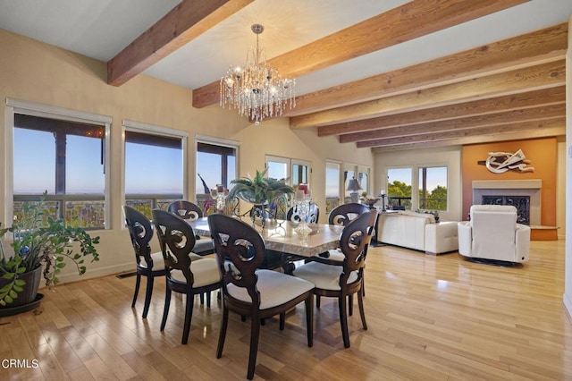 dining room with a notable chandelier, beam ceiling, and light hardwood / wood-style floors