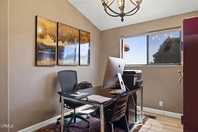 home office with light wood-type flooring, lofted ceiling, and an inviting chandelier