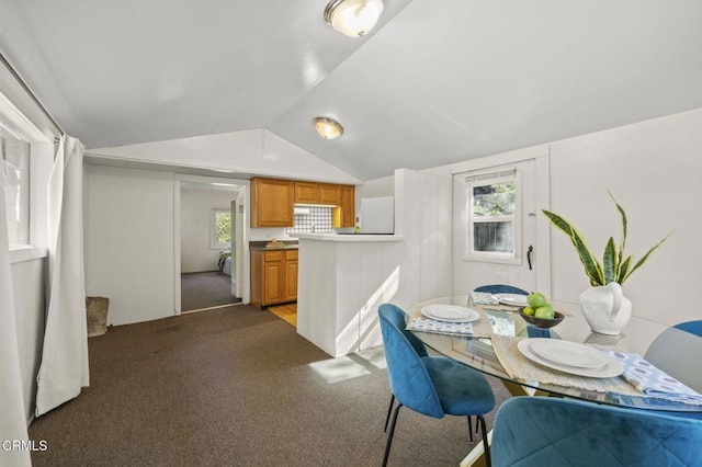 dining room with dark colored carpet, vaulted ceiling, and a wealth of natural light