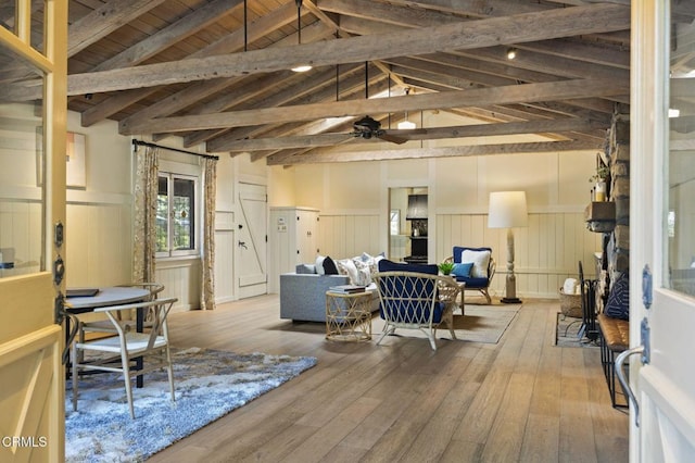 living room featuring hardwood / wood-style flooring, ceiling fan, and vaulted ceiling with beams