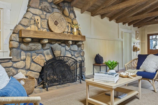 living room with lofted ceiling with beams, light wood-type flooring, a fireplace, and wood ceiling