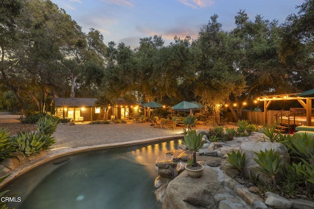 pool at dusk featuring an outbuilding and a patio