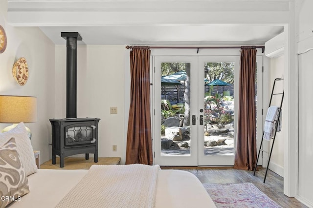 bedroom featuring light hardwood / wood-style flooring, a wood stove, access to outside, and french doors