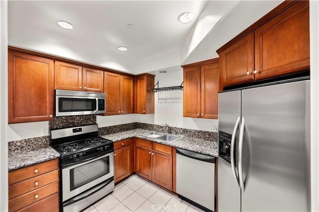 kitchen featuring stone counters, light tile patterned floors, sink, and appliances with stainless steel finishes