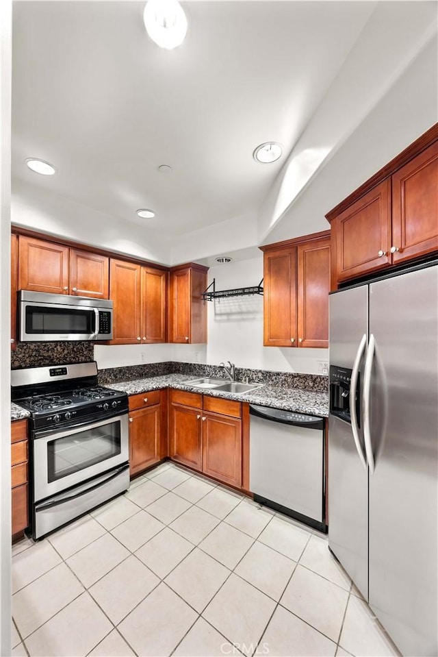 kitchen featuring sink, light tile patterned flooring, stainless steel appliances, and stone countertops