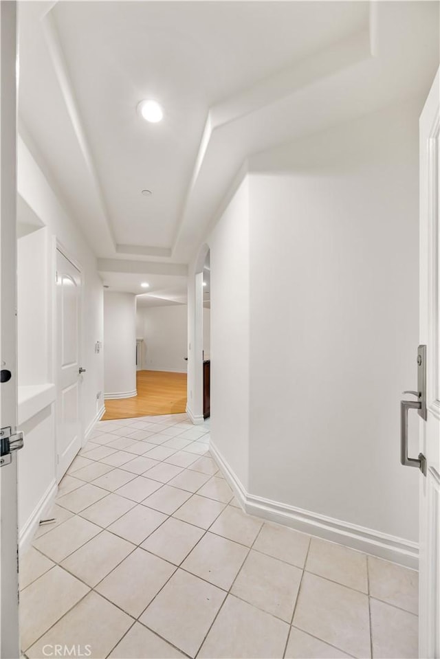 hallway featuring light tile patterned floors and a raised ceiling