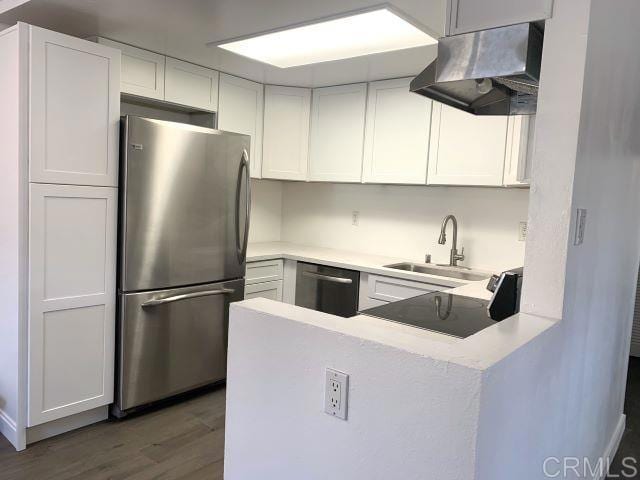 kitchen with kitchen peninsula, appliances with stainless steel finishes, dark wood-type flooring, sink, and white cabinetry