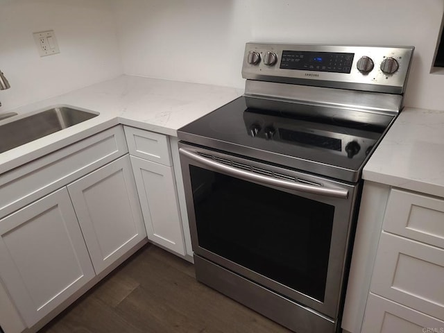 kitchen with stainless steel electric stove, light stone counters, white cabinets, and sink