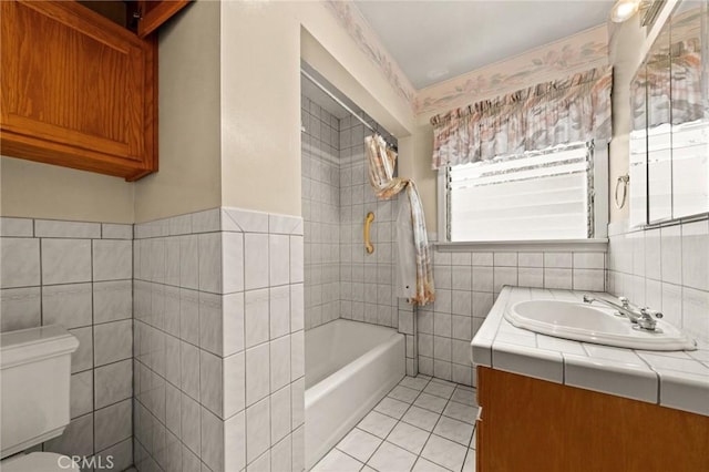 bathroom featuring vanity, a bathtub, tile patterned flooring, toilet, and tile walls