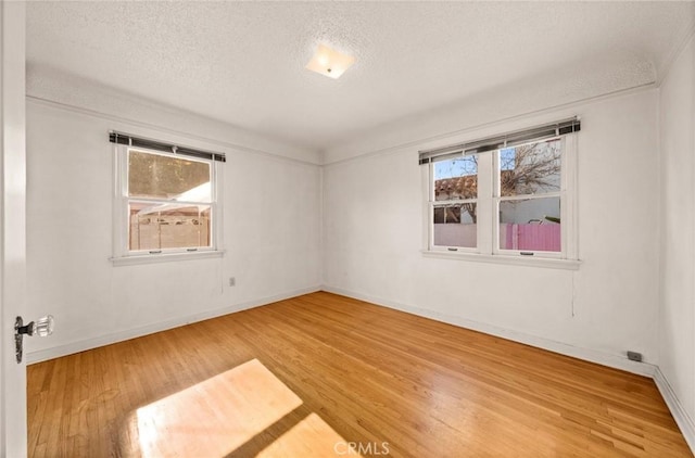 empty room with hardwood / wood-style floors, a healthy amount of sunlight, and a textured ceiling