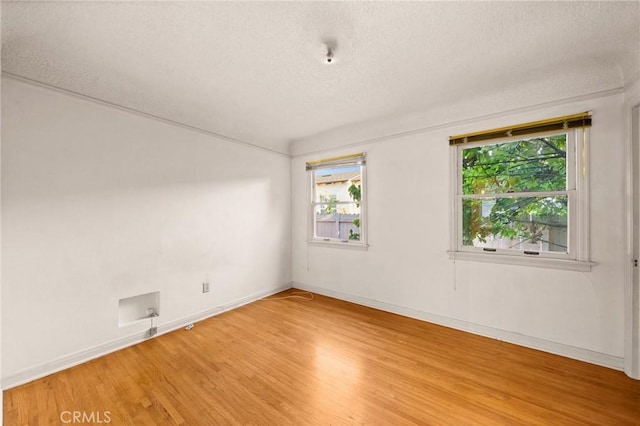 empty room with plenty of natural light, hardwood / wood-style floors, and a textured ceiling