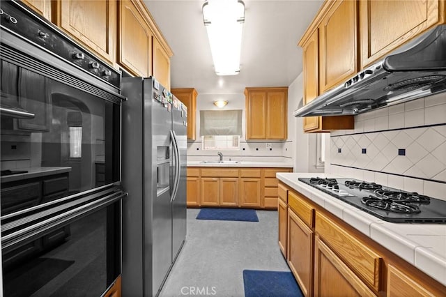 kitchen with white gas stovetop, sink, stainless steel refrigerator with ice dispenser, black double oven, and decorative backsplash