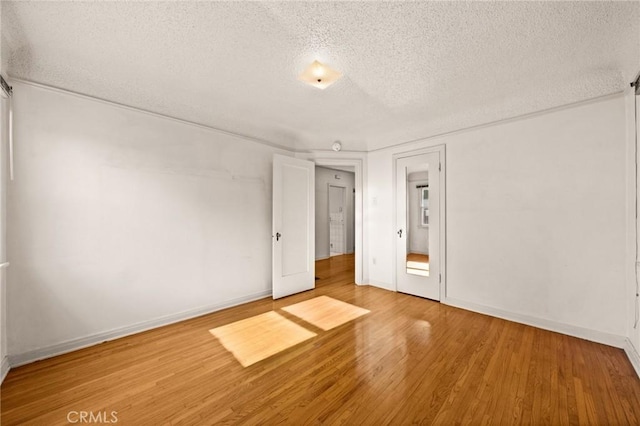 empty room with wood-type flooring and a textured ceiling