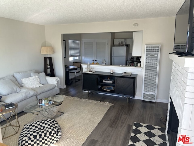 living room featuring dark hardwood / wood-style floors, a textured ceiling, and a brick fireplace