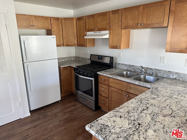 kitchen featuring dark hardwood / wood-style flooring, light stone counters, gas range, sink, and white refrigerator