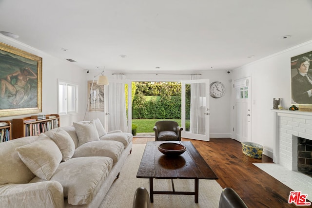 living room with dark hardwood / wood-style floors, a brick fireplace, plenty of natural light, and ornamental molding