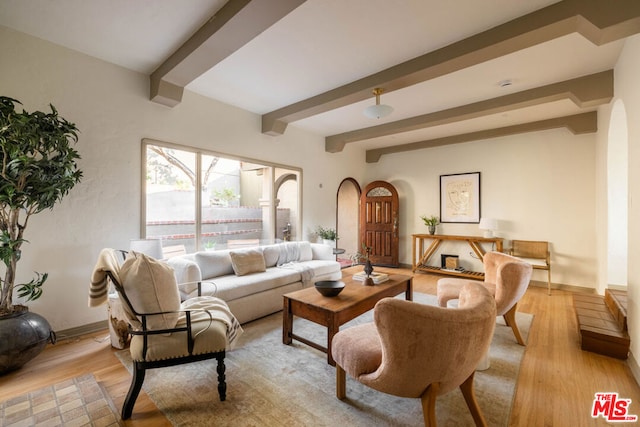 living room featuring beamed ceiling and light hardwood / wood-style floors