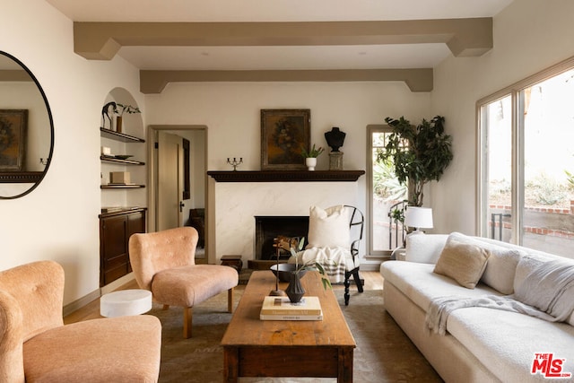 living room featuring dark wood-type flooring, a high end fireplace, built in shelves, and beamed ceiling