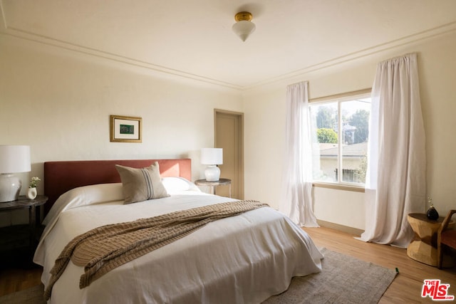 bedroom featuring crown molding and light wood-type flooring